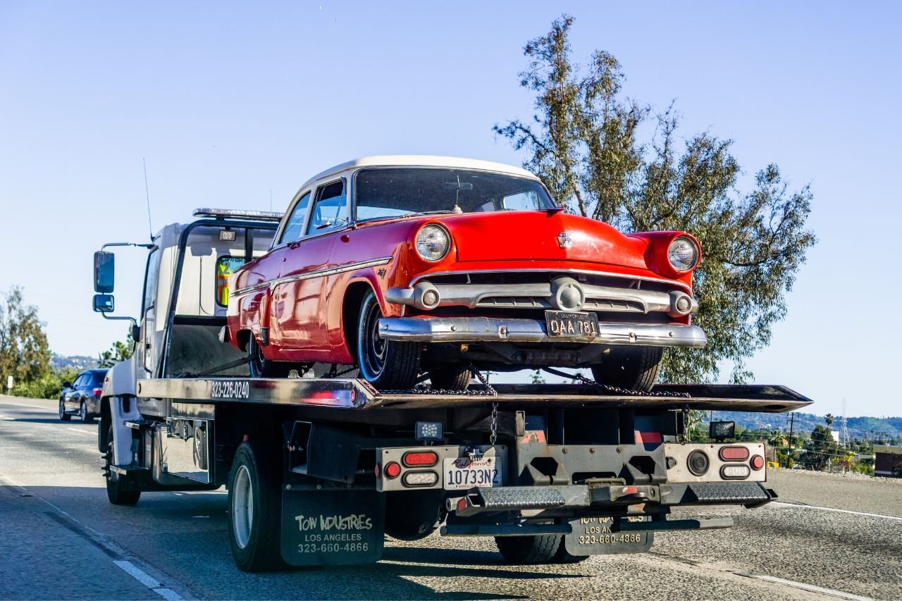 Vintage Car on Tow Truck A red vintage Ford on the back of a tow truck.